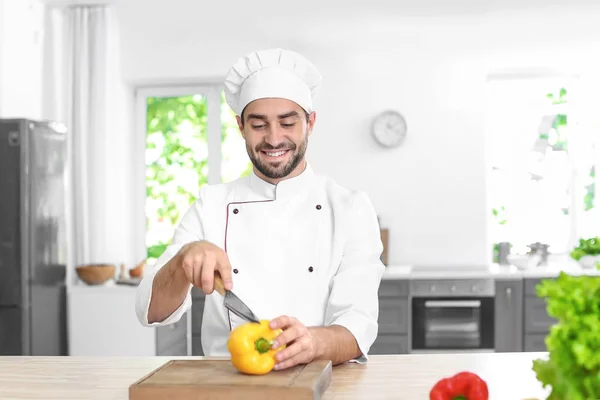 Jovem chef masculino corte páprica — Fotografia de Stock