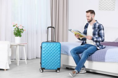 Genç adam otel odasında dergi okuma