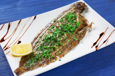 Plaka lezzetli kızarmış balık ve masada sos ile