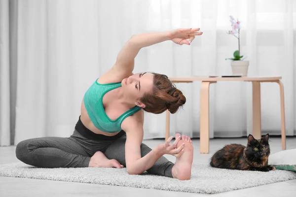 Junge Frau mit Katze praktiziert Yoga — Stockfoto