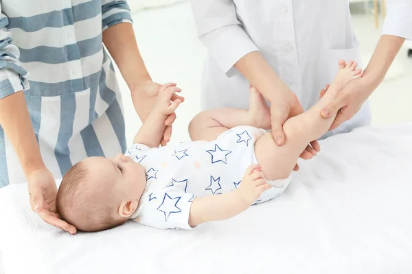 Jeune maman debout près du canapé tandis que le médecin examine bébé à la maison — Photo