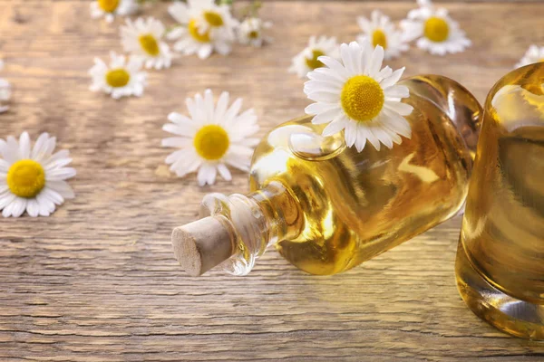 Bottles of essential oil and chamomile flowers — Stock Photo, Image