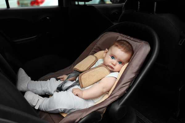 Adorable baby resting in child safety seat inside of car