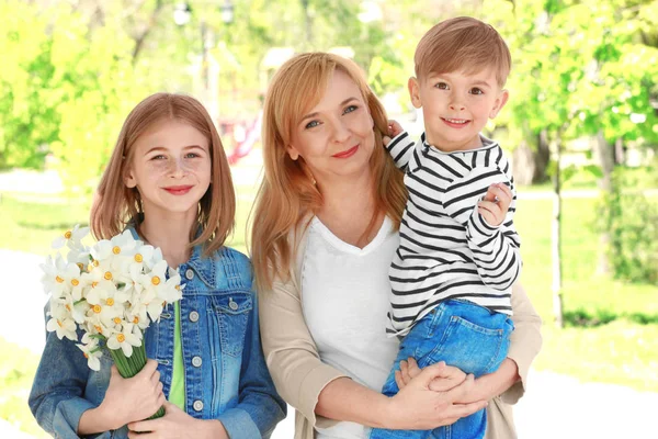 Lindos niños felices con abuela en el parque de primavera —  Fotos de Stock