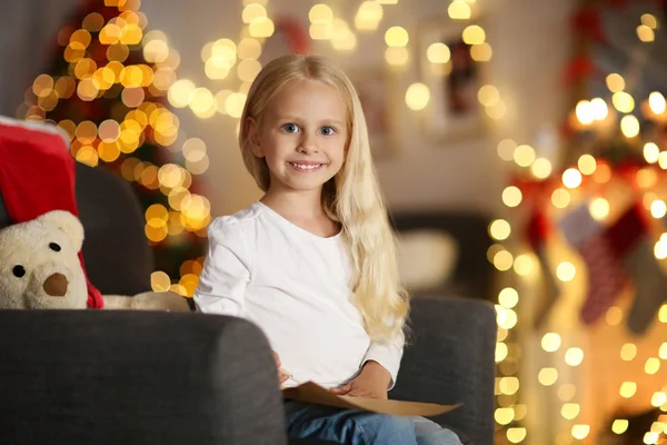 Schattig meisje zit in de leunstoel en schrijven van de brief aan de Kerstman thuis — Stockfoto