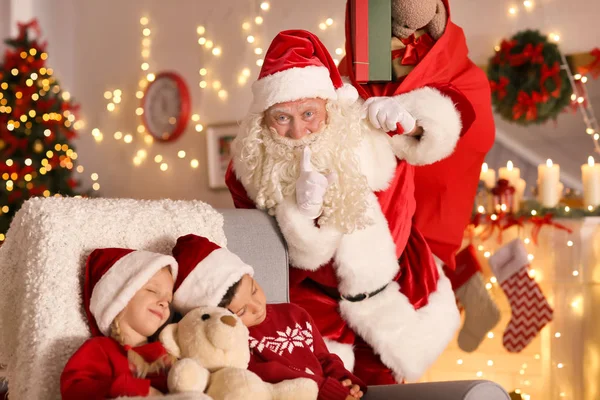 Настоящий Санта рядом со спящими детьми в номере с красивыми рождественскими украшениями — стоковое фото