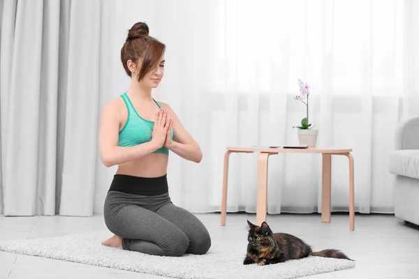 Mujer joven con gato practicando yoga — Foto de Stock