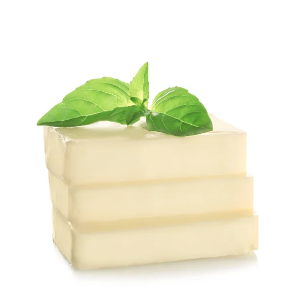 Bloc de beurre coupé avec des feuilles de basilic frais — Photo