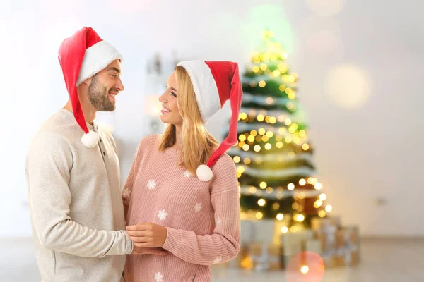 Mutlu çiftimiz Noel Baba şapkaları, Noel için dekore edilmiş salon içinde