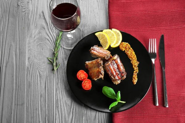 Plate with delicious ribs on wooden table — Stock Photo, Image