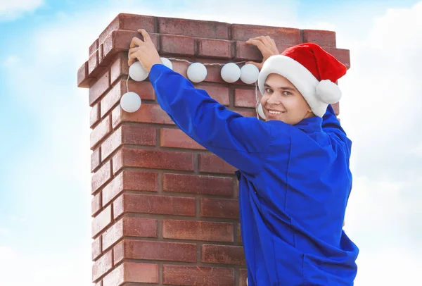 Uomo in cappello Santa decorazione camino con ghirlanda per Natale — Foto Stock