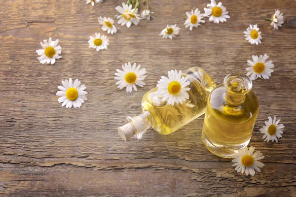 Bottles of essential oil and chamomile flowers — Stock Photo, Image