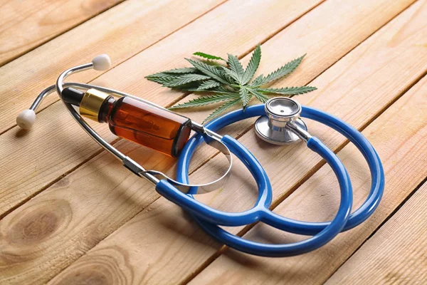 Stethoscope with hemp leaves and bottle of oil — Stock Photo, Image