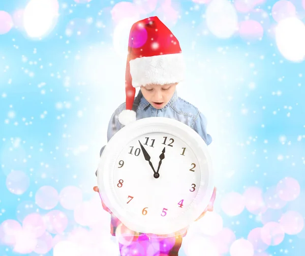 Niedliches Kleines Mädchen Mit Weihnachtsmütze Und Uhr Auf Verschwommenem Licht — Stockfoto