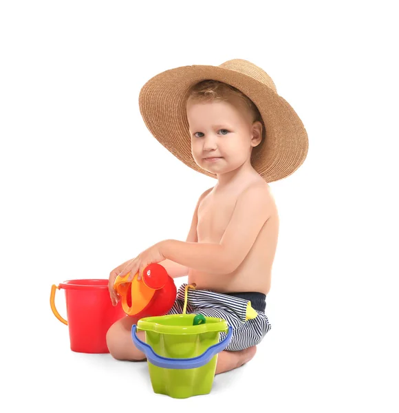 Ładny mały chłopiec w duży kapelusz słomkowy, bawi się zabawkami plaży na białym tle — Zdjęcie stockowe