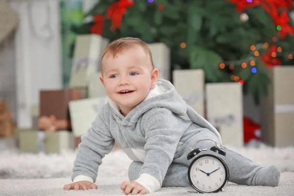 Niedliches kleines Baby mit Uhr zu Hause. Weihnachts-Countdown-Konzept — Stockfoto
