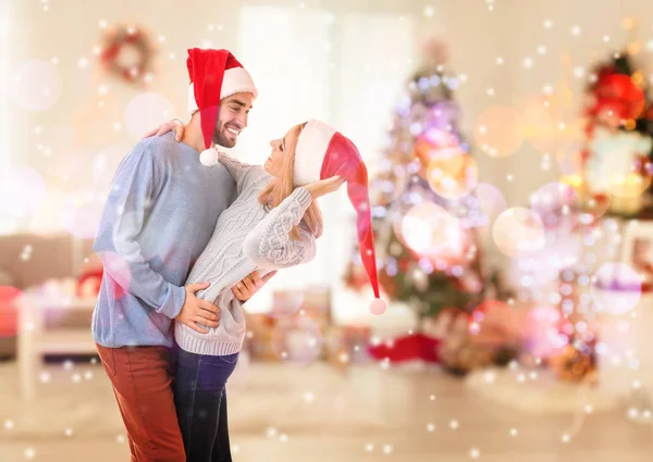 Coppia felice in Babbo Natale cappelli che ballano in salotto decorato per Natale — Foto Stock
