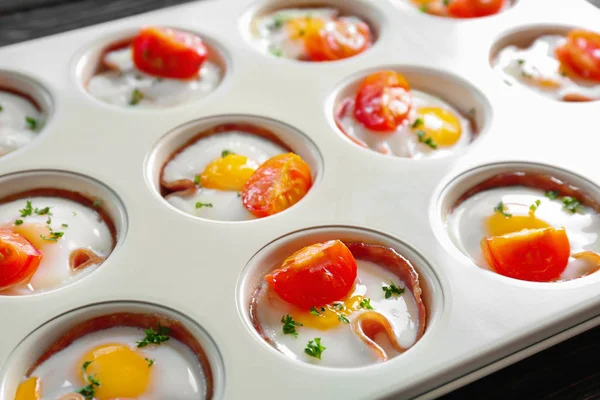 Форма для випічки зі смачними яйцями, помідорами та шинкою — стокове фото