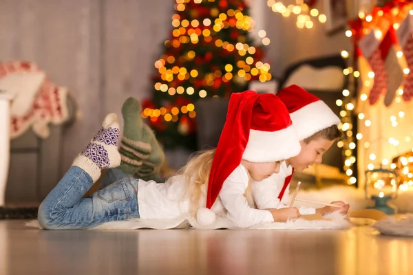 Bonito crianças escrevendo carta para Papai Noel no quarto decorado para o Natal — Fotografia de Stock