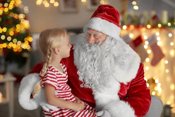 Noel Baba'nın kucağına güzel Noel süslemeleri ile odada oturan küçük kız