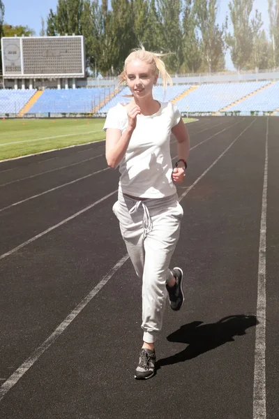 Молодая красивая женщина бежит на стадионе — стоковое фото