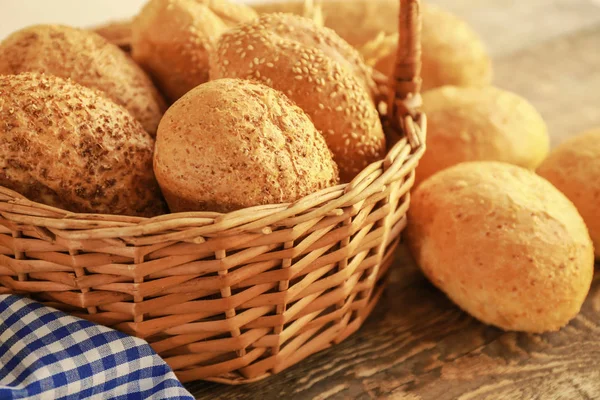 Красивая композиция с плетеной корзиной и вкусным хлебом на деревянном столе — стоковое фото
