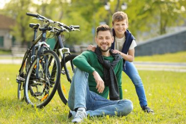 Baba ve oğul çimenlerin üzerinde oturan 