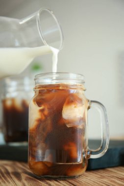 Soğuk bira kahve ahşap masa üzerinde mason kavanoza süt dökme