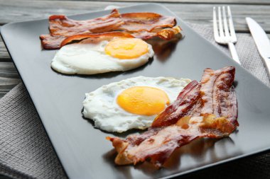 Sahanda yumurta ve domuz pastırması ahşap masa üzerinde birlikte