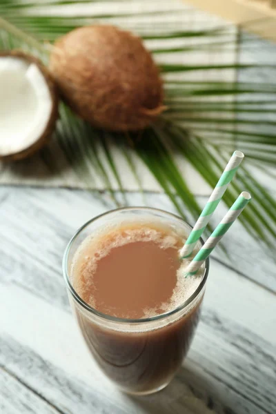 Стекло с кокосовым кофе и соломинками на деревянном столе — стоковое фото