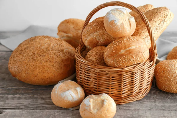 Bela composição com cesta de vime e delicioso pão na mesa de madeira — Fotografia de Stock