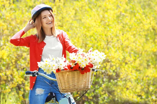 Ung flicka med cykel och korg med blommor — Stockfoto