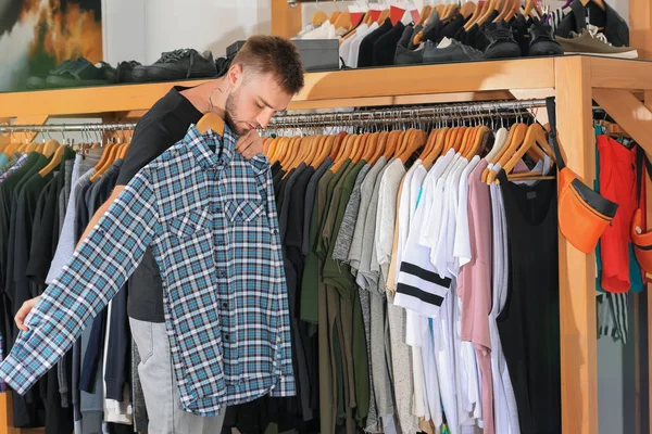 Молодой человек выбирает одежду в торговом центре — стоковое фото