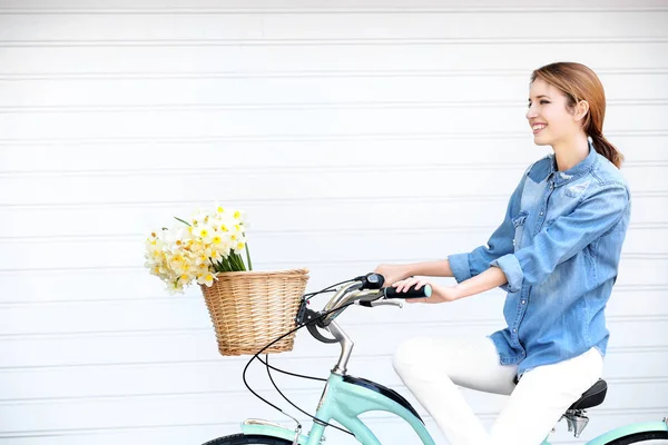 Ung flicka med cykel och korg med blommor — Stockfoto