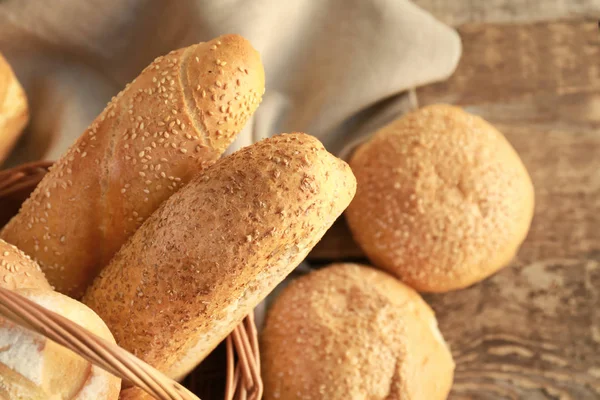 Cesta de mimbre con delicioso pan en mesa de madera —  Fotos de Stock