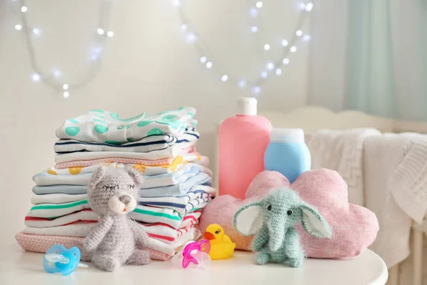 Söta stickade leksaker, babykläder och tillbehör på bordet i rummet — Stockfoto