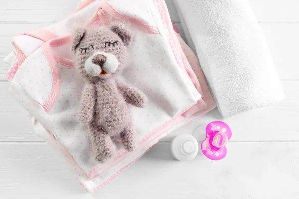Knitted toy bear, baby clothes and accessories on table — Stock Photo, Image