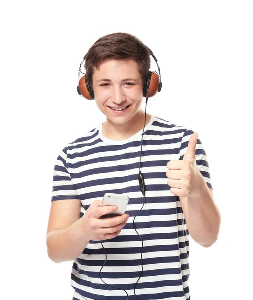 Cute teenage boy with mobile phone and headphones listening to music on white background — Stock Photo, Image
