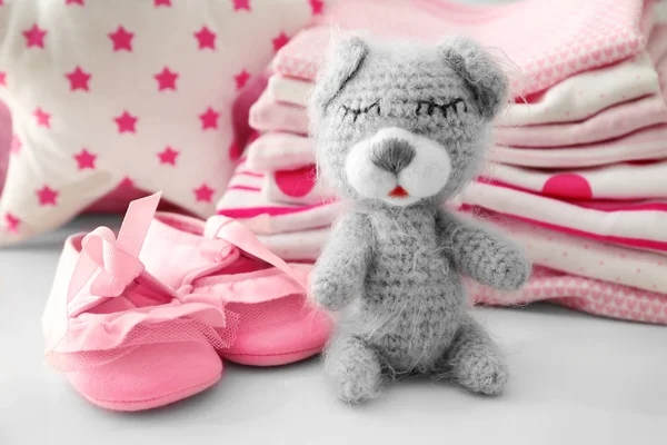 Pletená hračka medvěd a dětské oblečení na stole — Stock fotografie