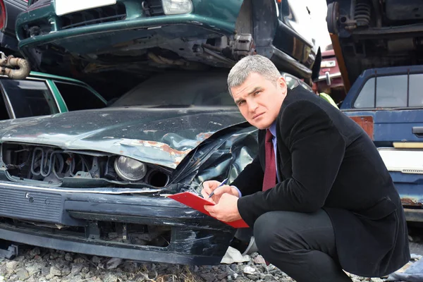 Страховий чоловік перевіряє зламаний автомобіль — стокове фото