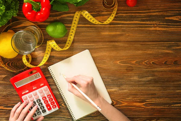 Mujer joven calculando calorías en la mesa. Concepto de pérdida de peso —  Fotos de Stock