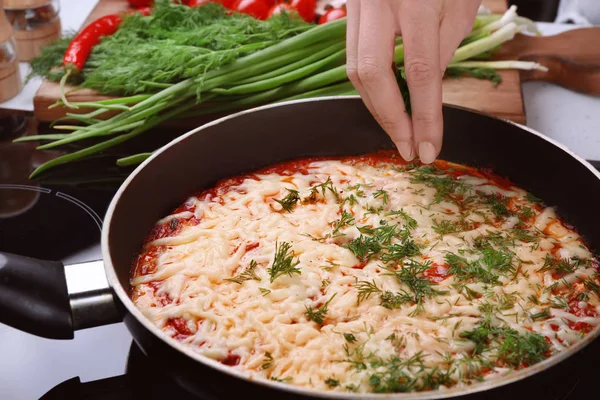 Woman pouring dill on eggs in purgatory — Stock Photo, Image