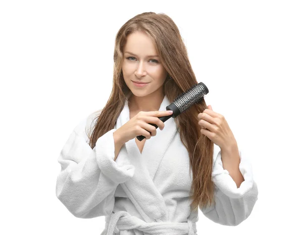 Piękna młoda kobieta czesanie jej włosy po prysznic na białym tle — Zdjęcie stockowe