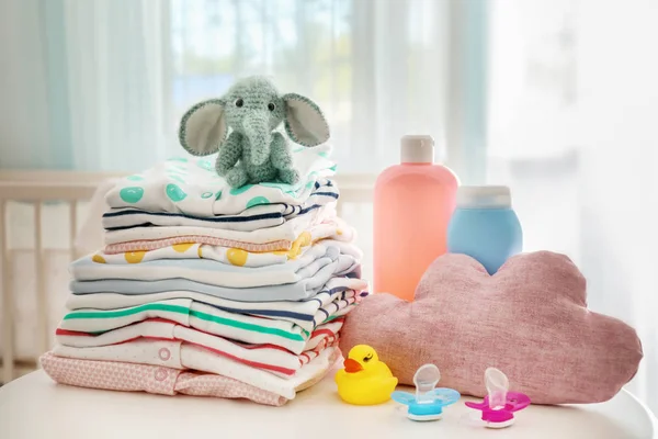 Knitted toy elephant, baby clothes and accessories on table in room — Stock Photo, Image