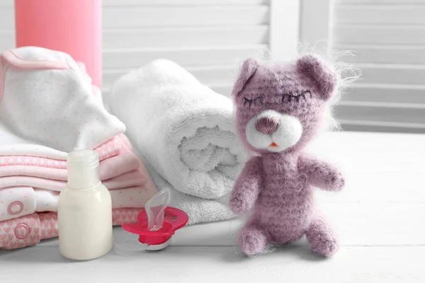 Orso giocattolo lavorato a maglia, vestiti per bambini e accessori sulla tavola — Foto Stock