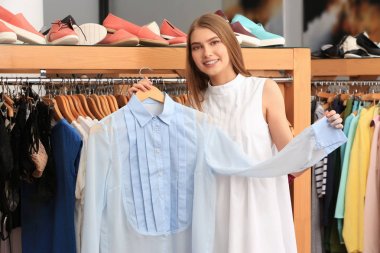 Young woman choosing clothes in mall clipart