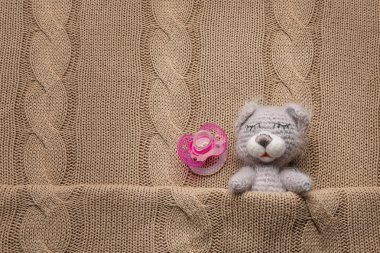 Sevimli el yapımı oyuncak ayı ve örme arka plan üzerinde emzik