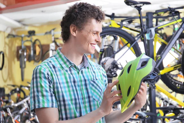 Jongeman fiets helm in winkel kiezen — Stockfoto