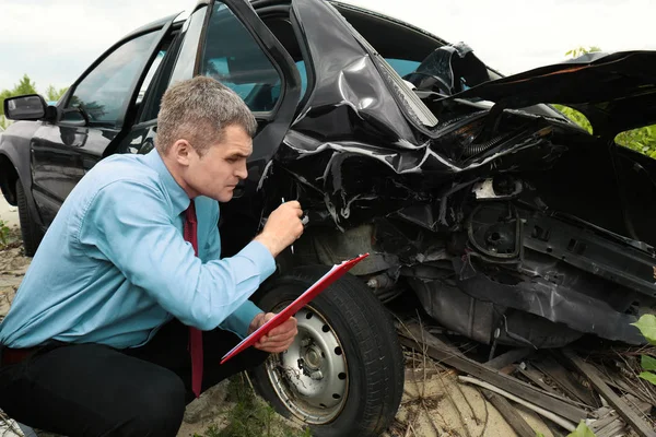 Страховий чоловік перевіряє зламаний автомобіль — стокове фото