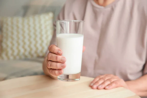 Old woman holding glass with milk